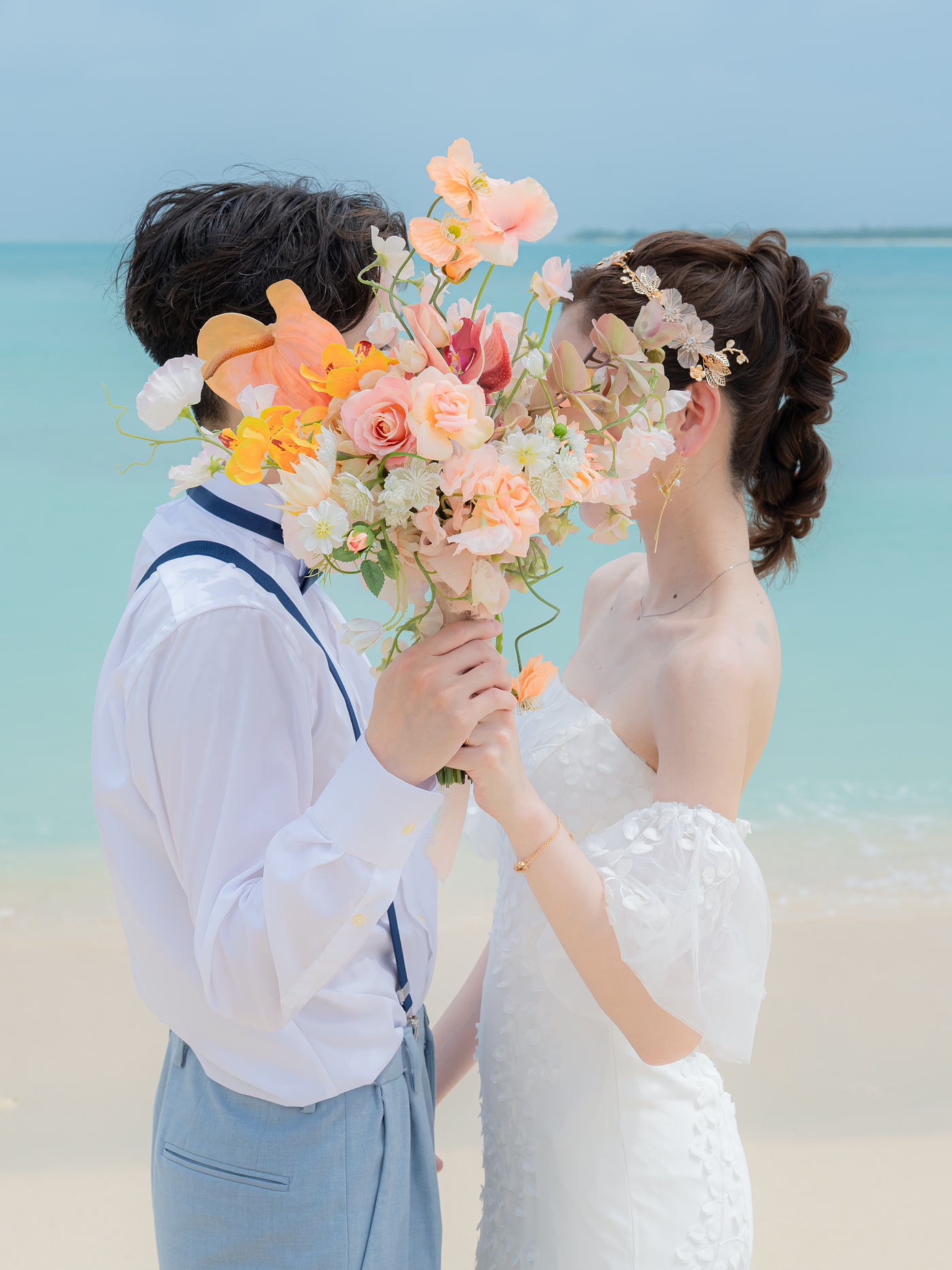 Couple holding a bouquet on a white-sand beach in Okinawa during a pre-wedding photoshoot